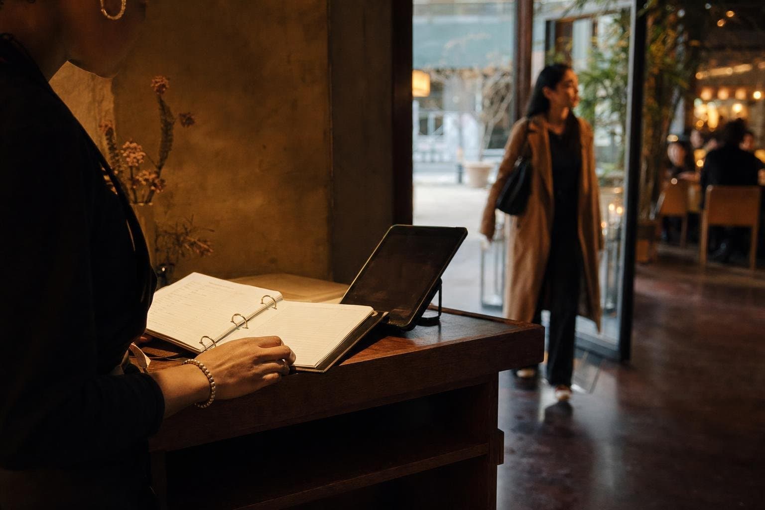 A reservation book open at a warmly lit restaurant host stand