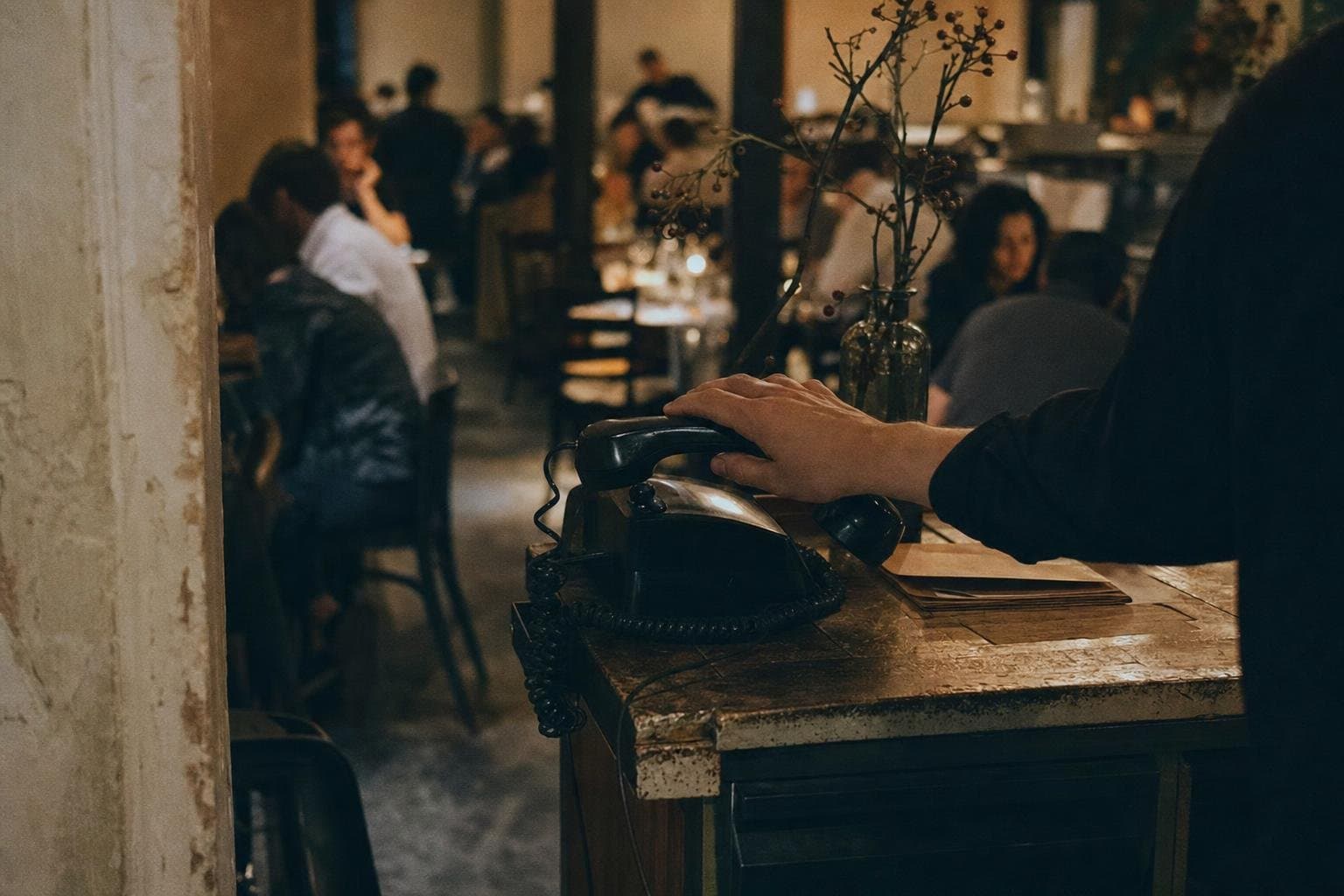 A phone at a restaurant host stand with a busy dining room behind