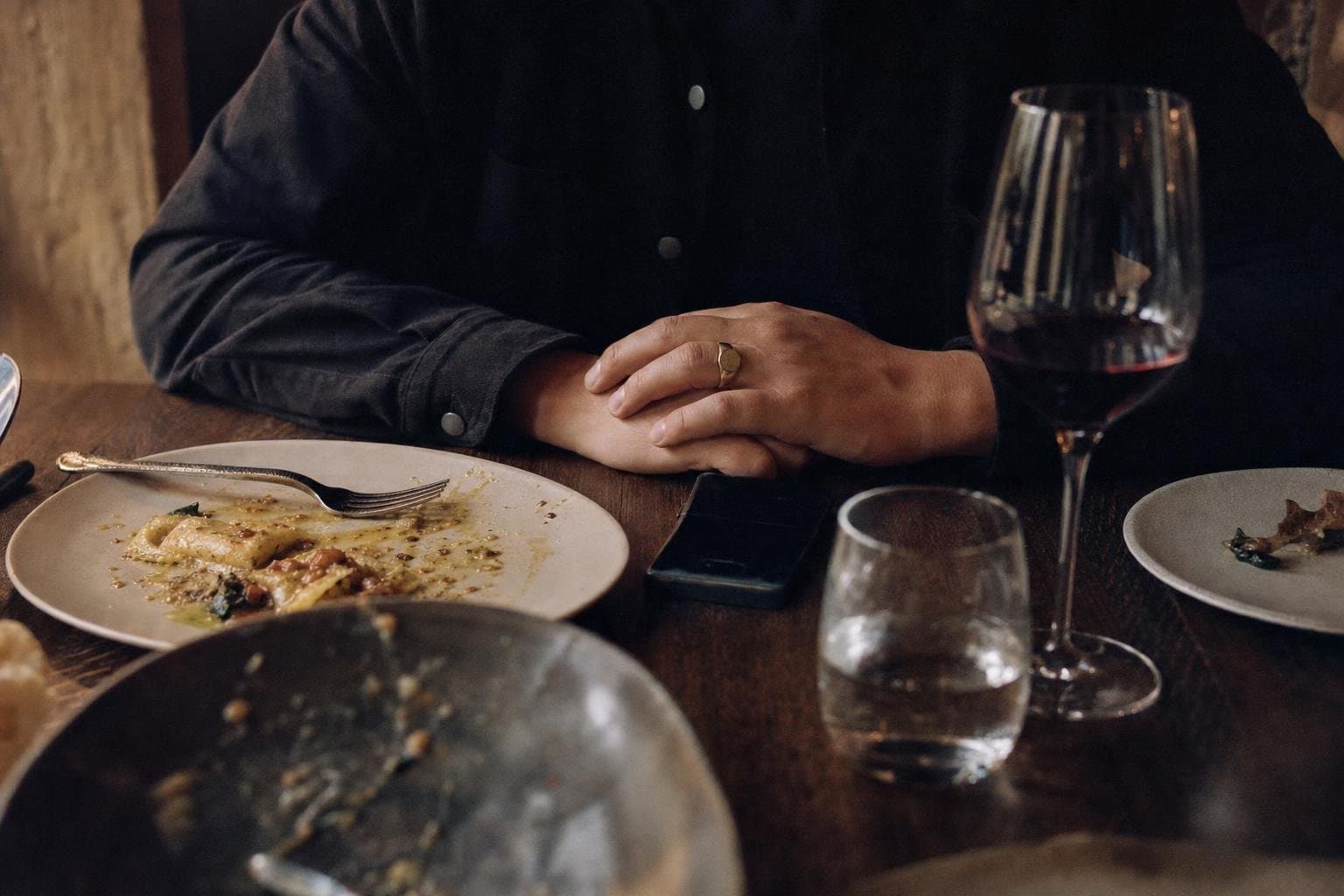 A guest's hands with a phone at a restaurant table after a meal